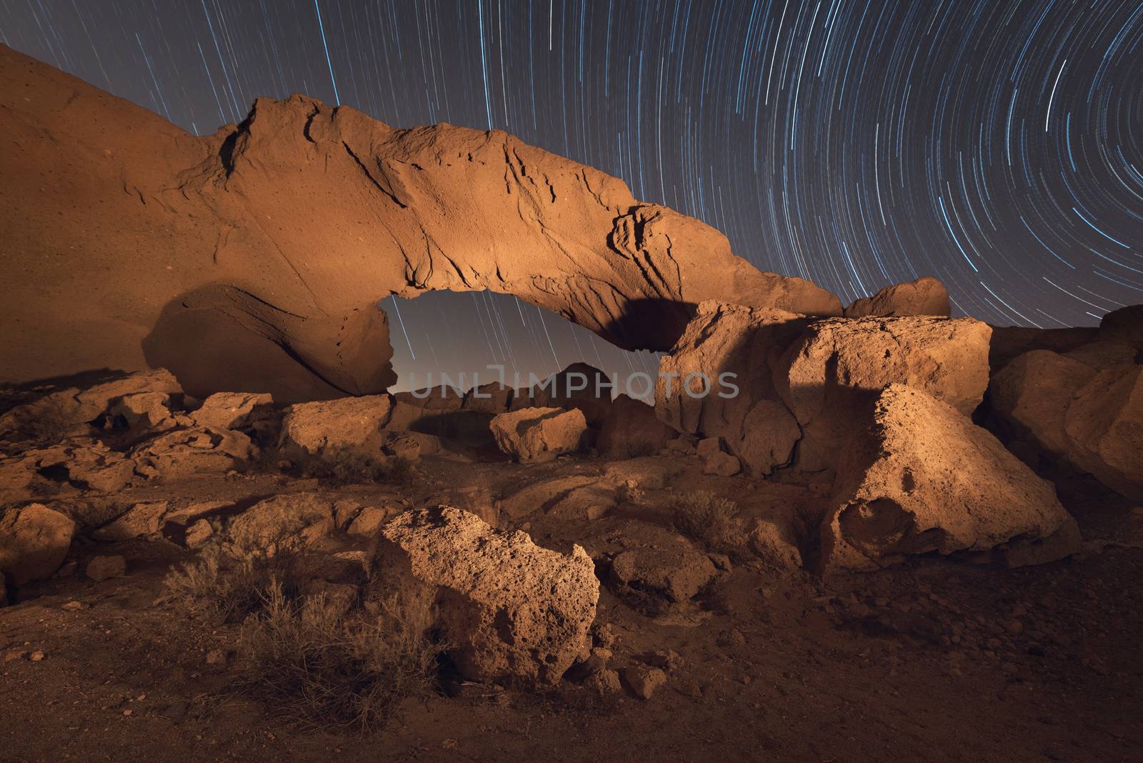 Star trails night landscape of a volcanic Rock arch in Tenerife, Canary island, Spain. by HERRAEZ