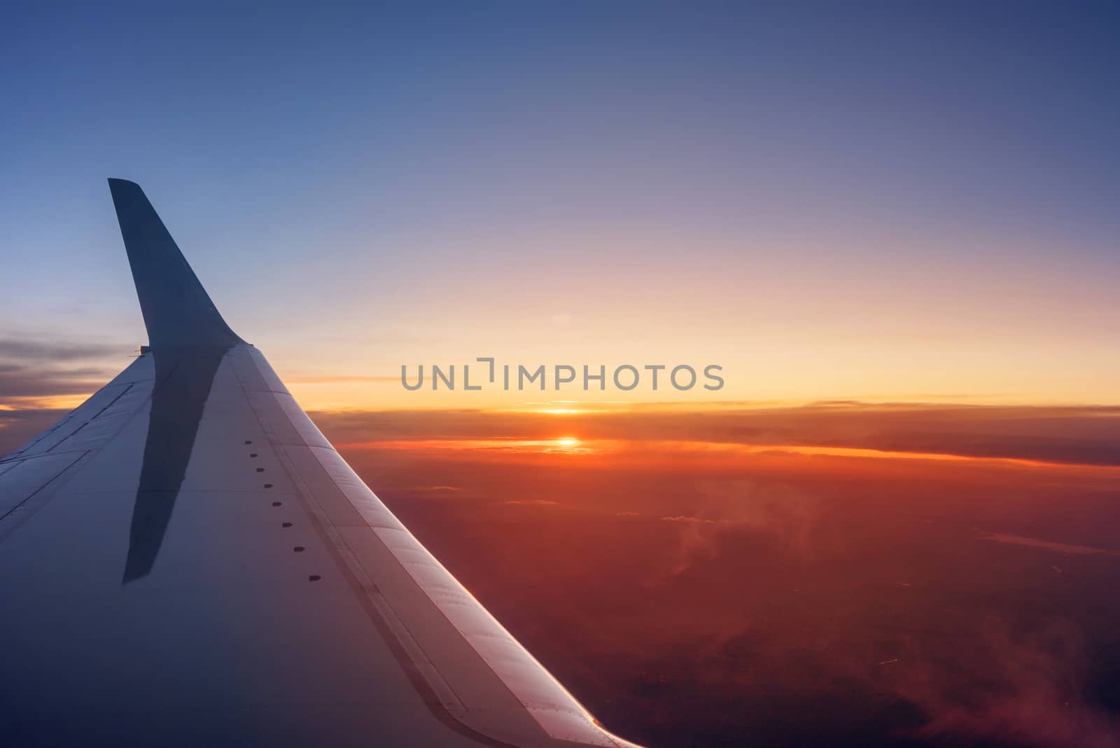 Airplane wing during a vibrant sunset by HERRAEZ