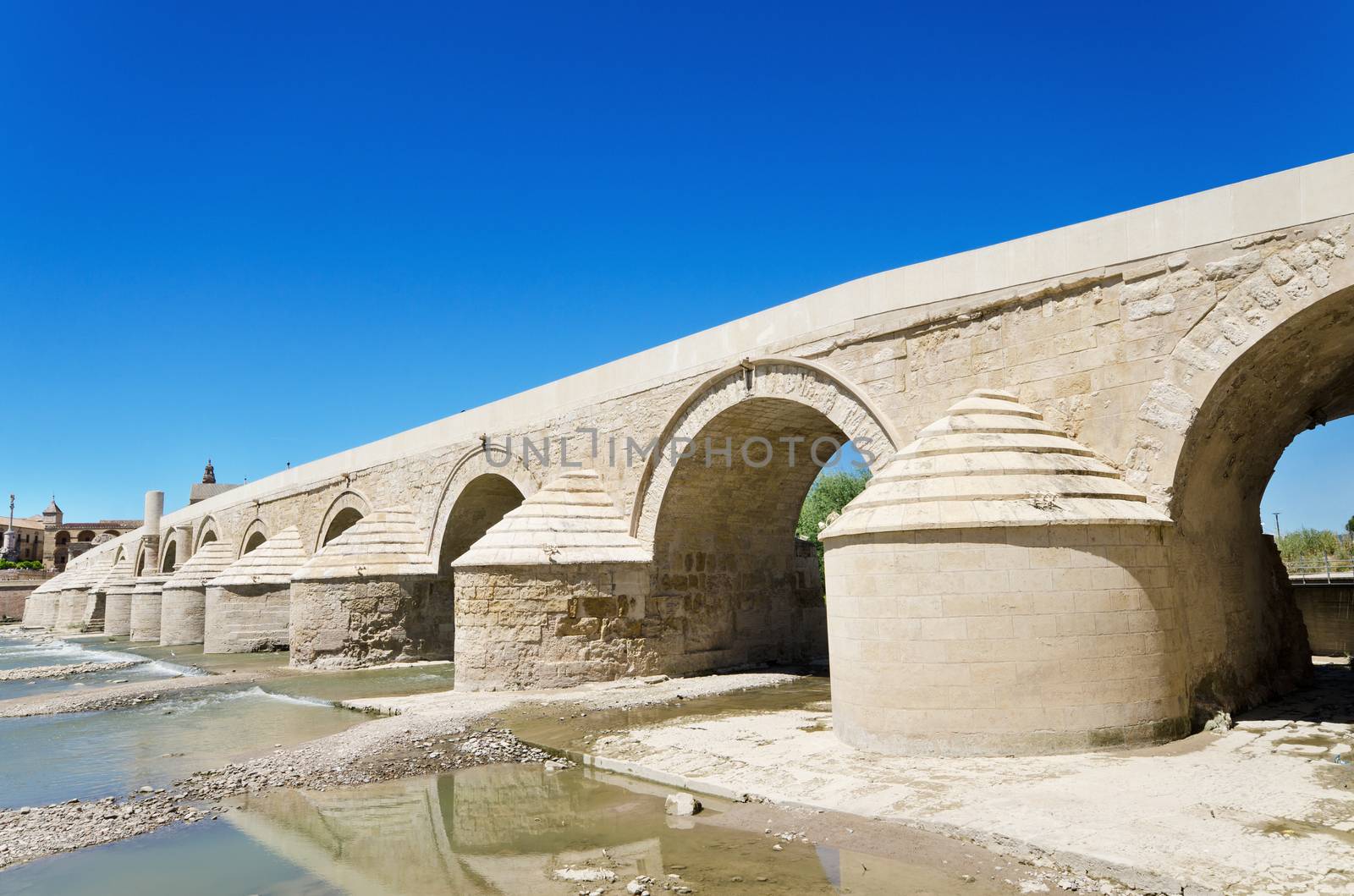 Roman bridge and Guadalquivir river over blue bright sky in Cordoba, Andalusia, Spain.