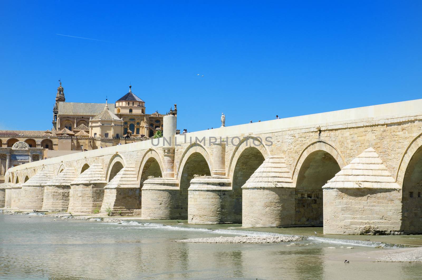 Arabic Mosque, Roman bridge and Guadalquivir river over blue bright sky in Cordoba, Andalusia, Spain.