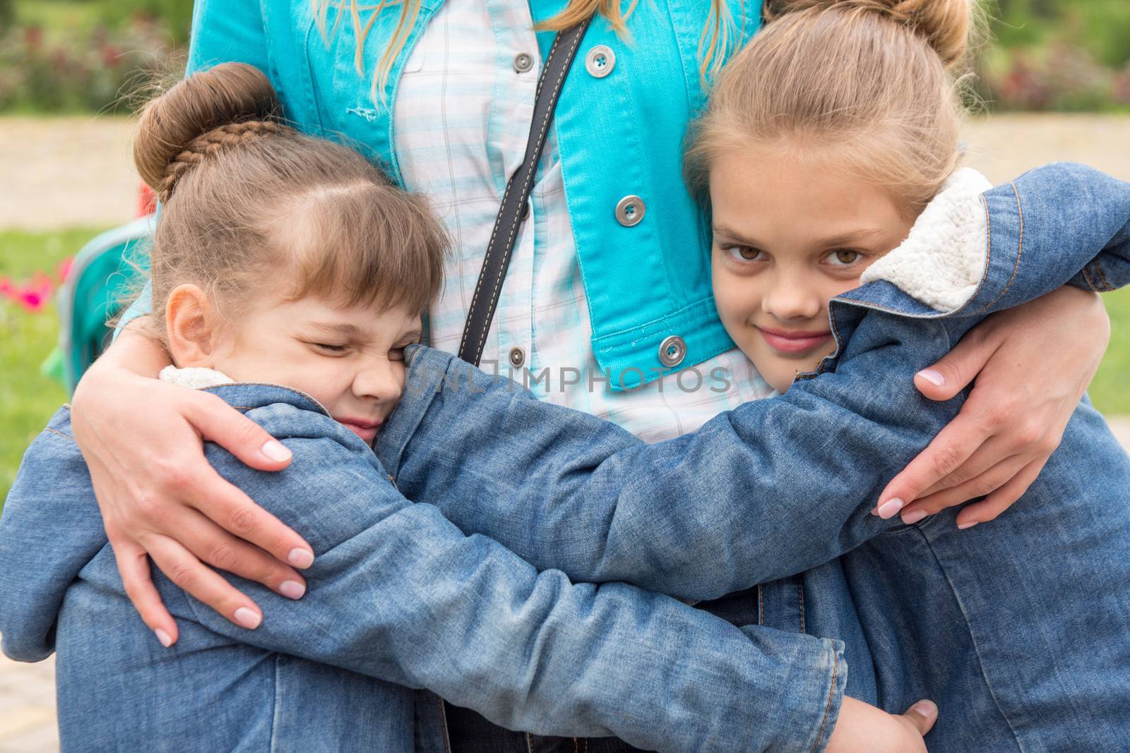 Two girls hug mother tightly