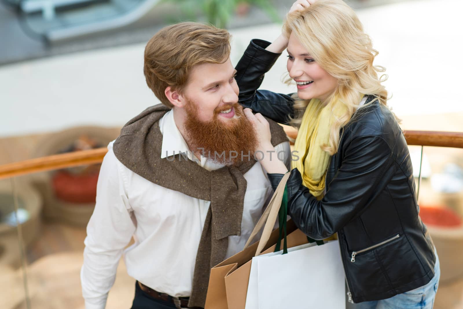 Happy beautiful young couple with shopping bags in mall