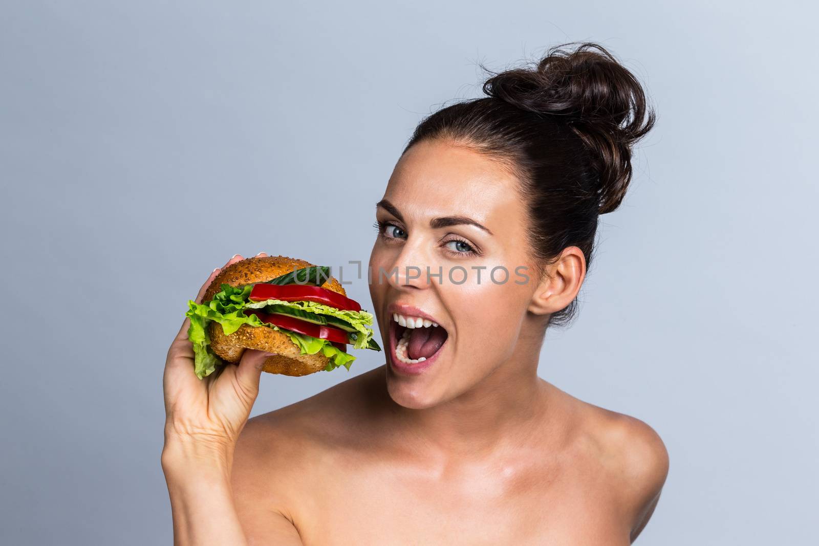 Young woman eating burger made of fruits and vegetables, healthy eating concept