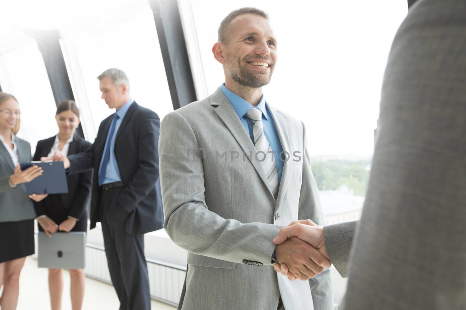 Business people shaking hands and smiling, finishing up a meeting in office