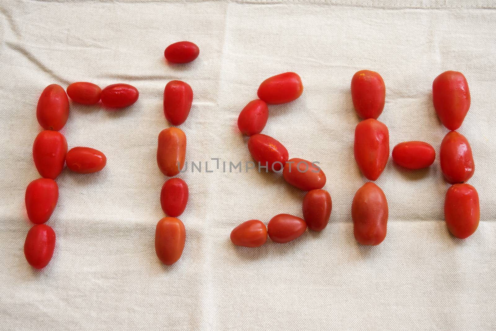 written fish made with fresh tomatoes on a white background