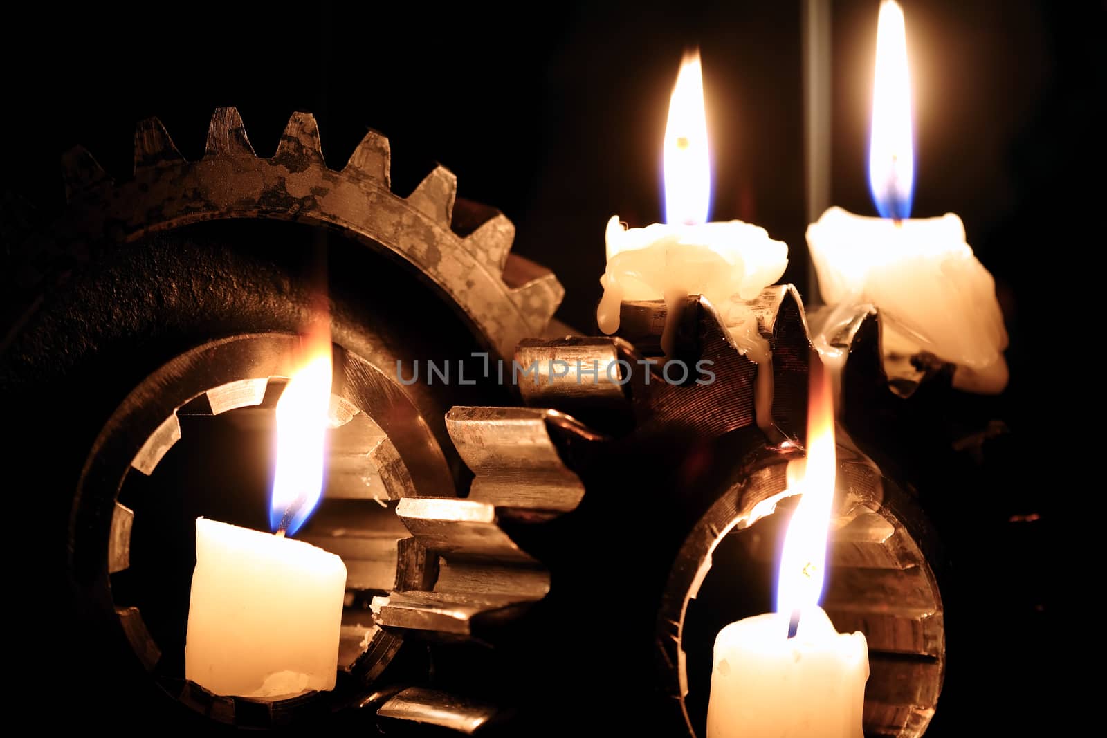 Lighting candles between old gears against dark background