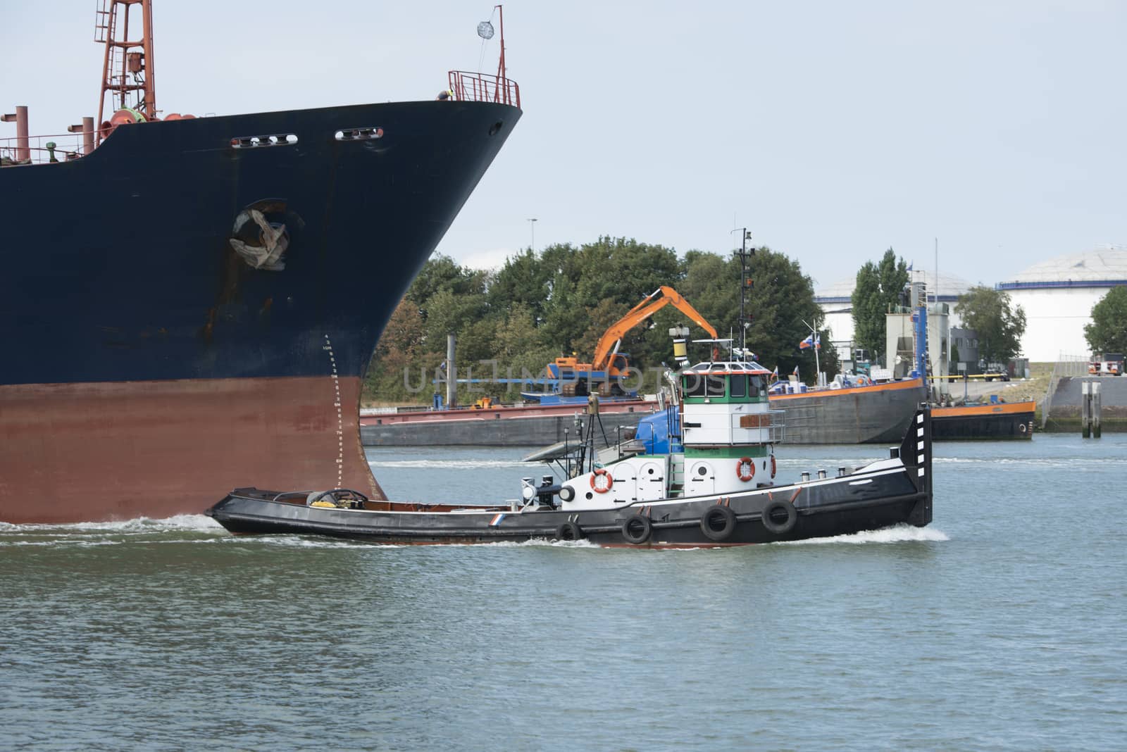 small tug boat pulling big ship by compuinfoto