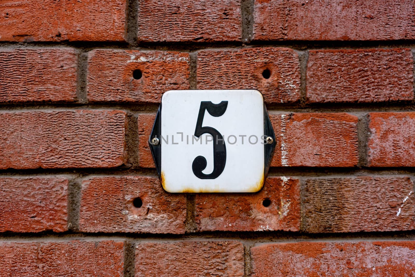 Enameled house number five on a brick wall