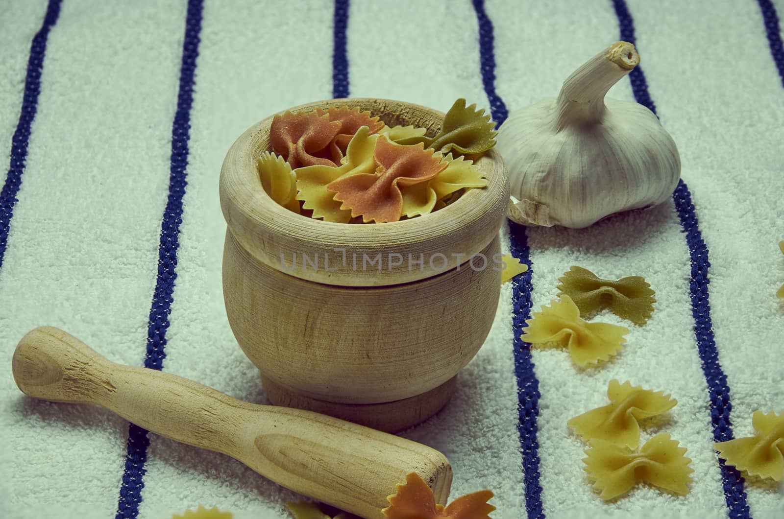 Wooden mortar filled with Italian pasta with garlic ingredients for preparation