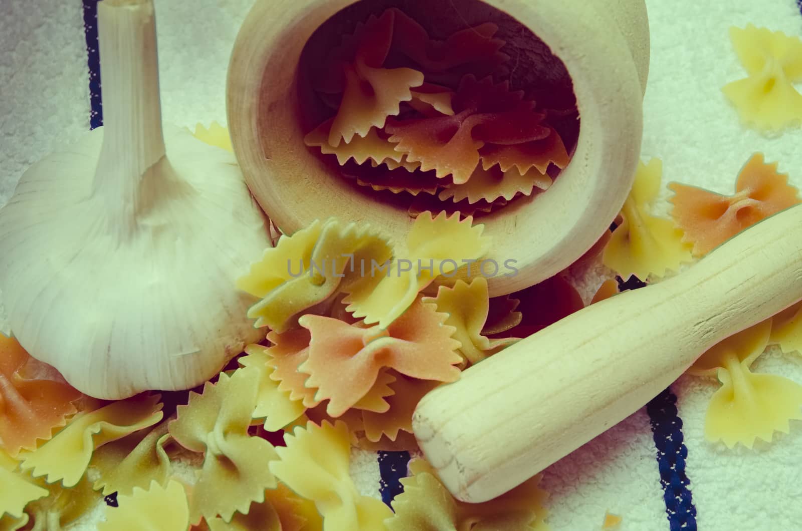 Wooden mortar filled with Italian pasta with garlic ingredients for preparation