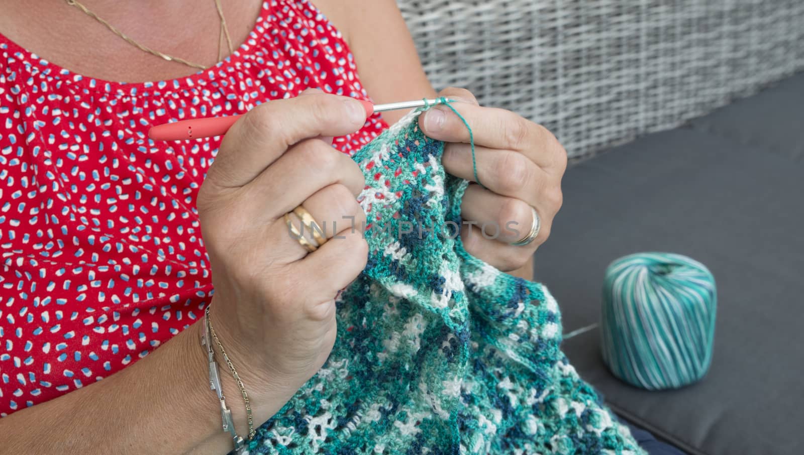 woman engaged in crocheting a sweater of blue wool