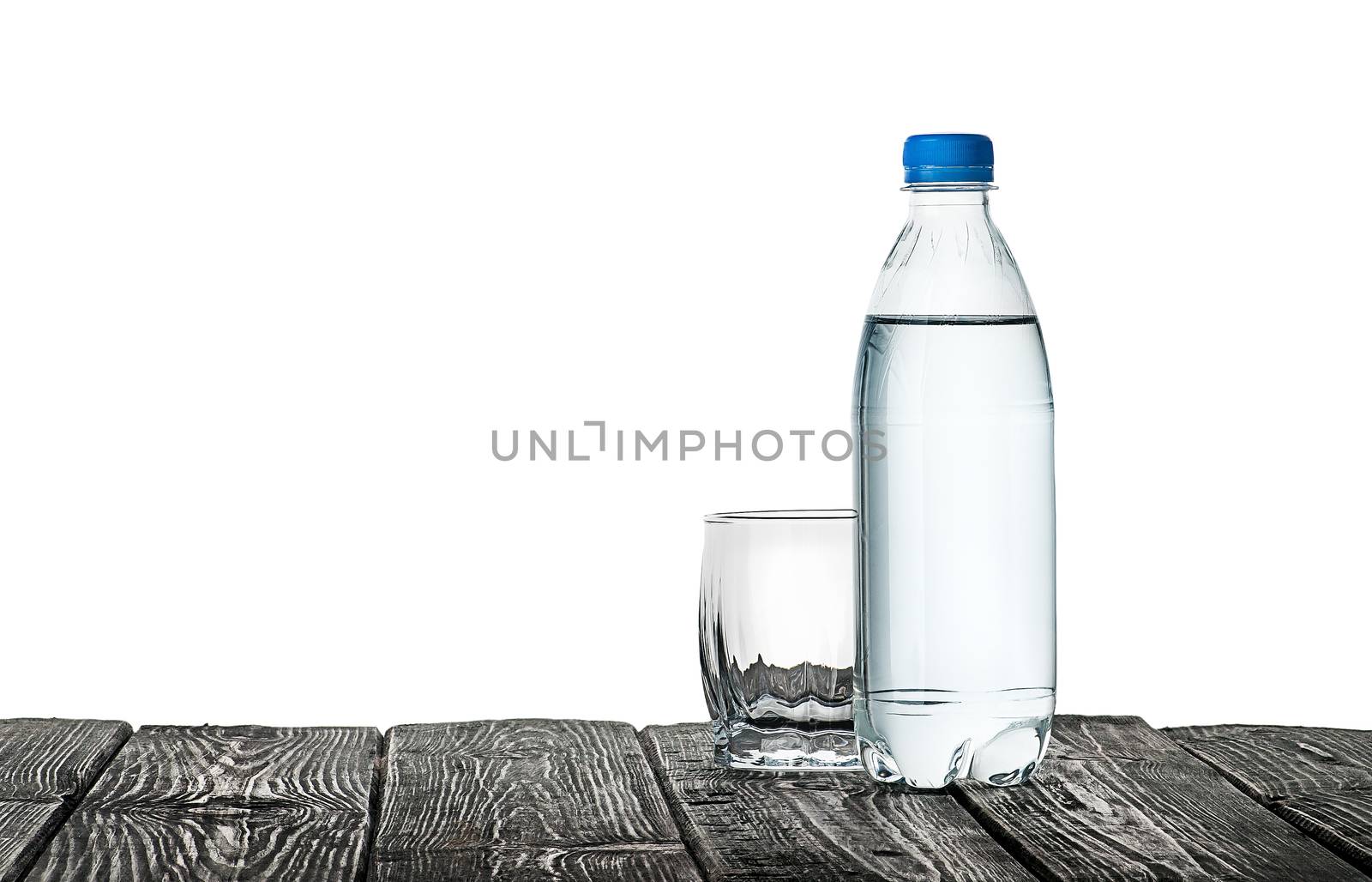 Empty glass and bottle of water. Plastic bottle on a wooden table. Isolated on white background.