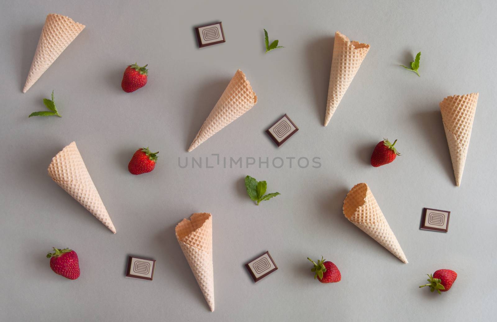 Top view of empty ice cream cones with fresh ingredients including strawberries, mint and chocolate