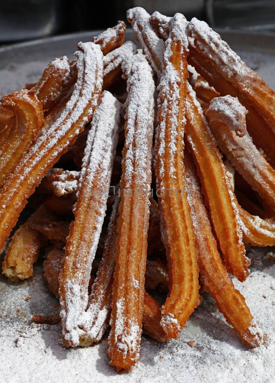 Heap of sweet fresh churros with sugar, traditional Spanish or Portuguese deep fried dough pastry snack cooked close up, high angle view