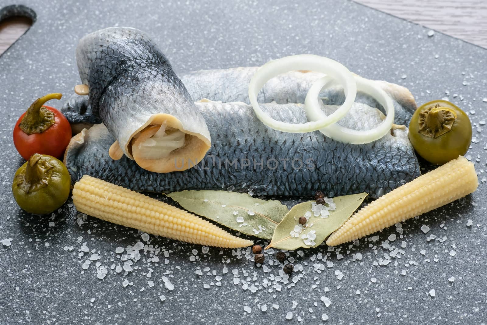 Saltwater marinated fish, cold appetizer. Herring fillet marinated on black cutting board