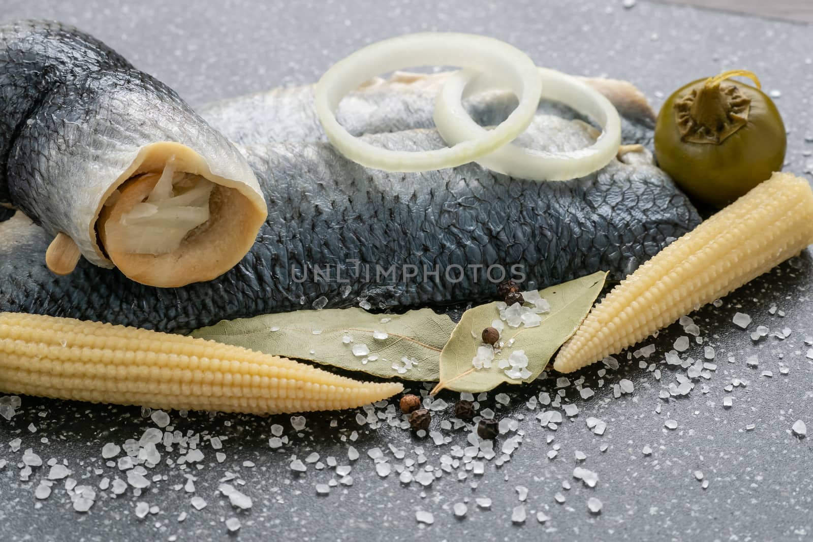 Saltwater marinated fish, cold appetizer. Herring fillet marinated on black cutting board