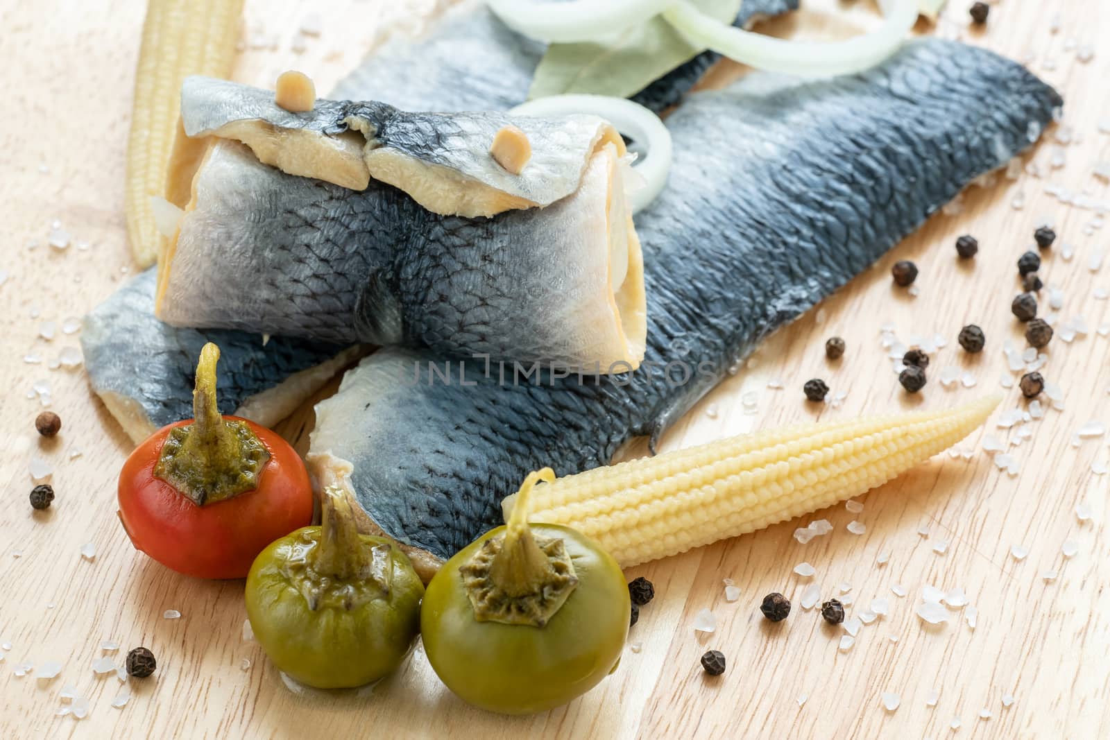 Saltwater marinated fish, cold appetizer. Herring fillet marinated on wooden cutting board