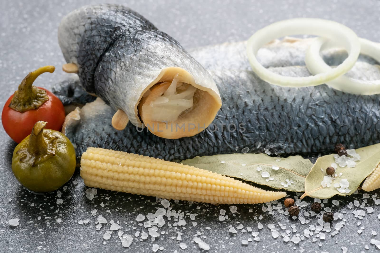 Saltwater marinated fish, cold appetizer. Herring fillet marinated on black cutting board