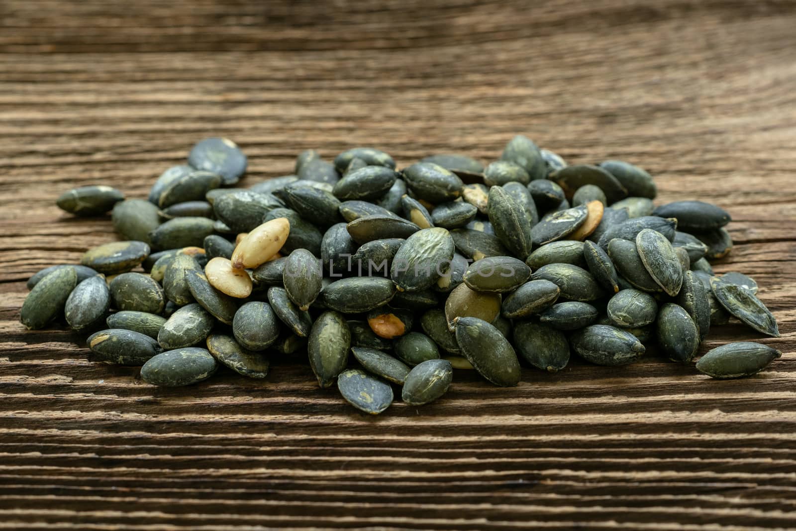 Pumpkin seeds seasoned using sea salt. Pumpkin seeds over wooden table.