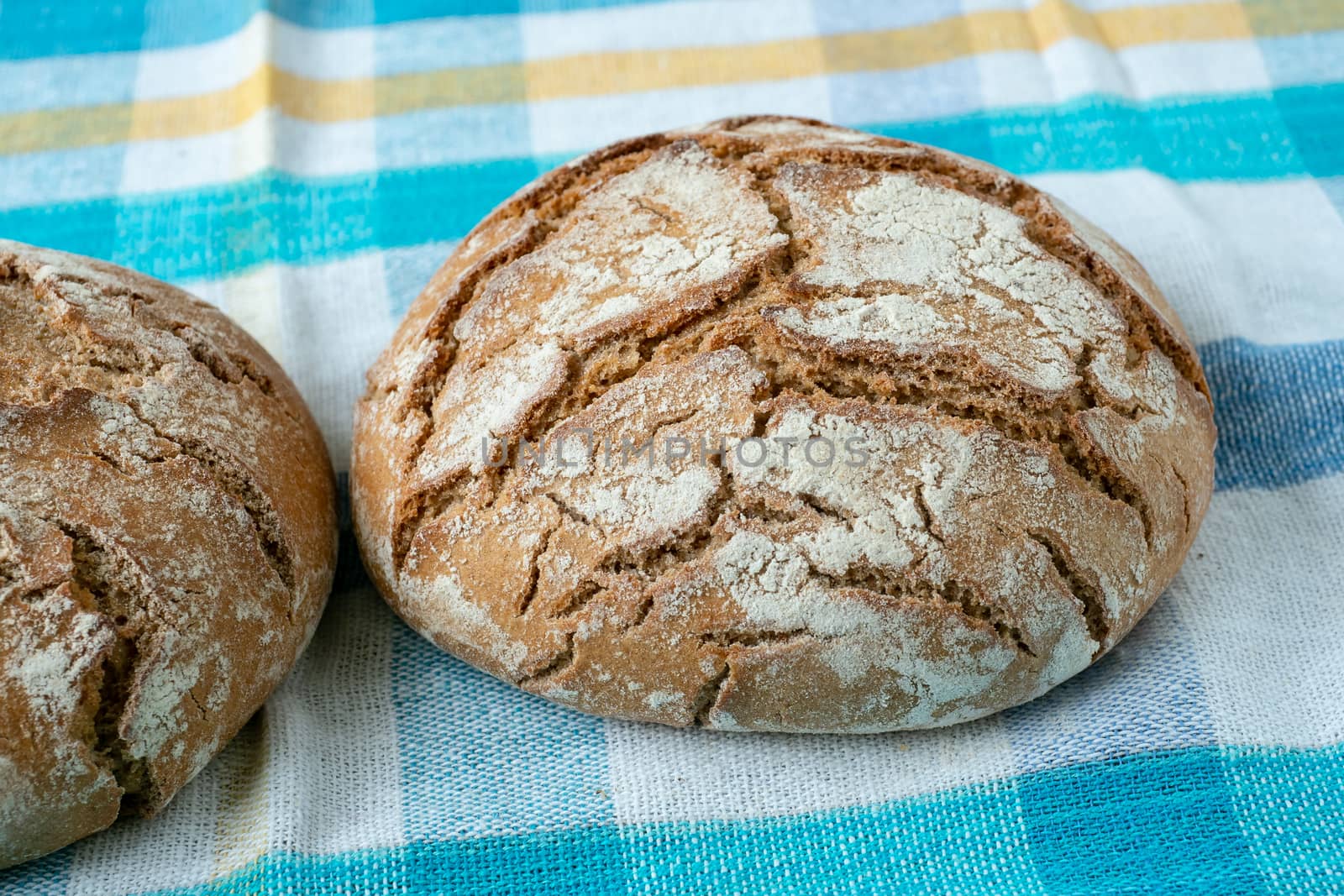 Fresh rustic bread on a checkered towel by xtrekx