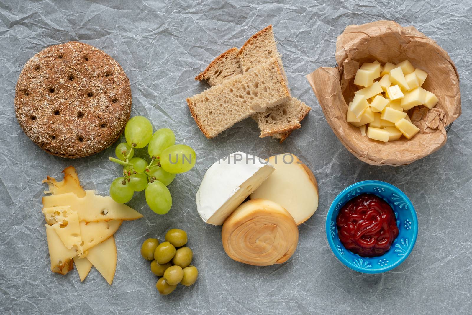 Cold appetizer. Cold cuts. Different snacks on a white crumpled paper, from above.