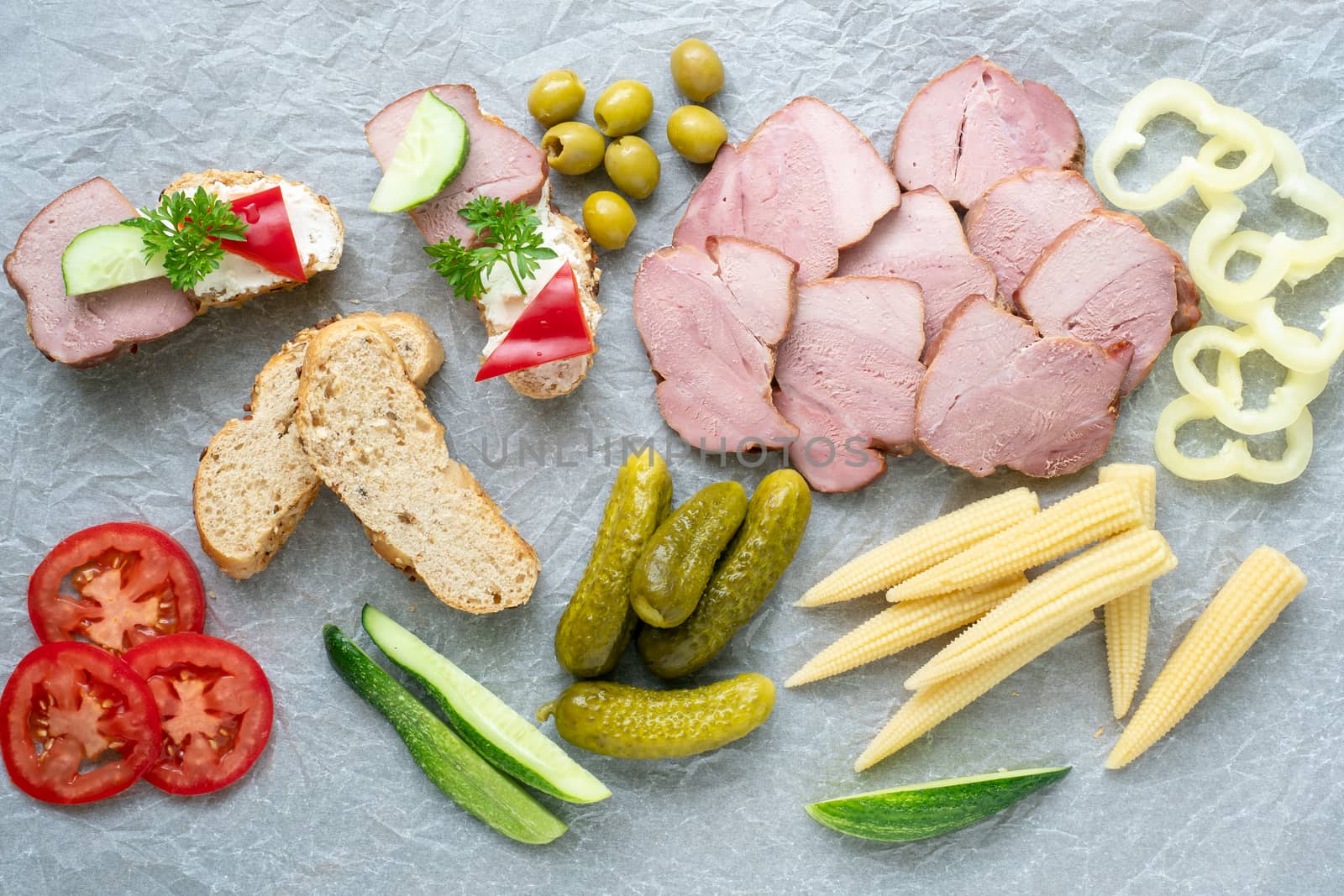 Cold appetizer. Cold cuts. Different snacks on a white crumpled paper, from above.