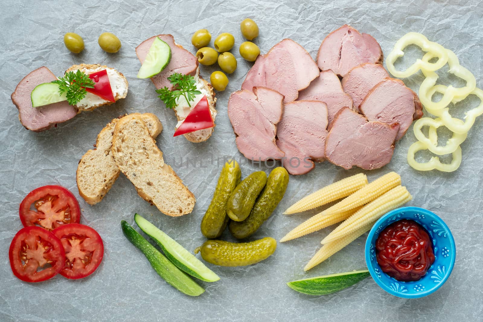 Cold appetizer. Cold cuts. Different snacks on a white crumpled paper, from above.