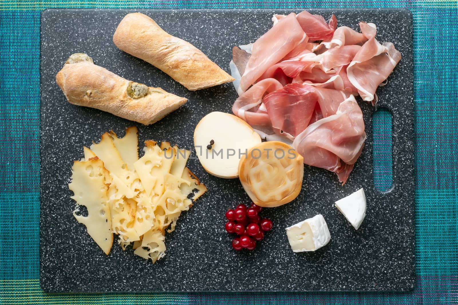 Cold appetizer. Cold cuts. Prosciutto,cheese on cutting board isolated on blue background, top view