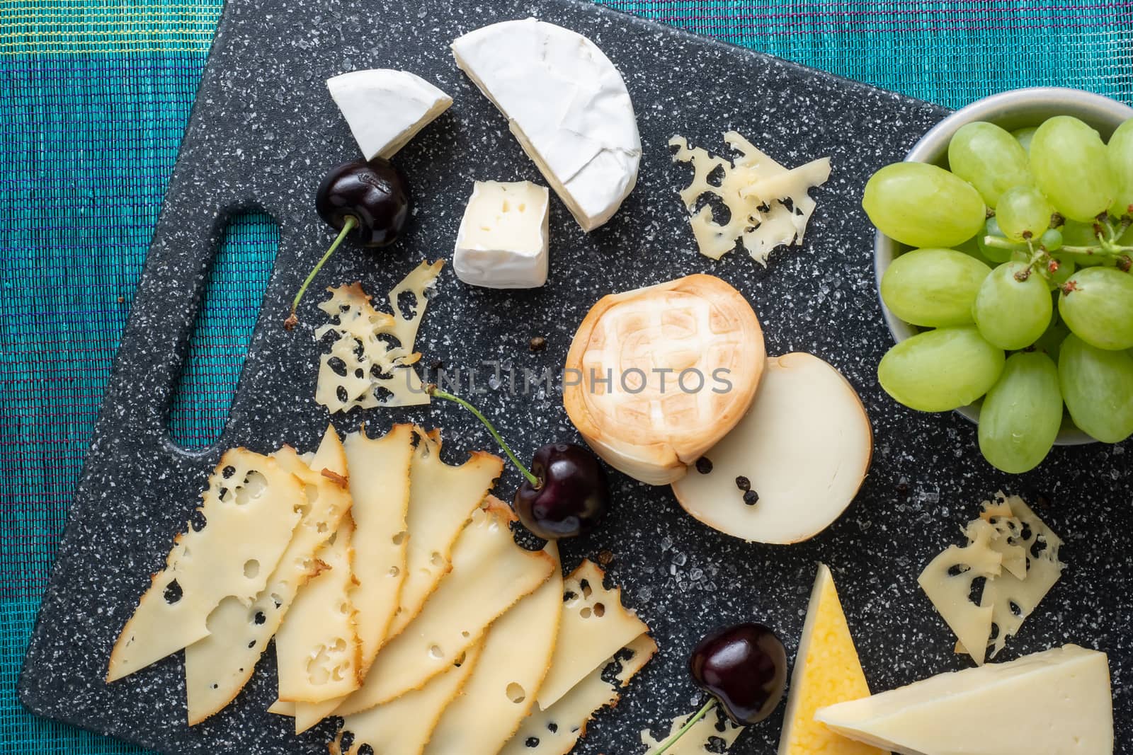 Cold appetizer. Cold cuts. Cheese on cutting board isolated on blue background, top view