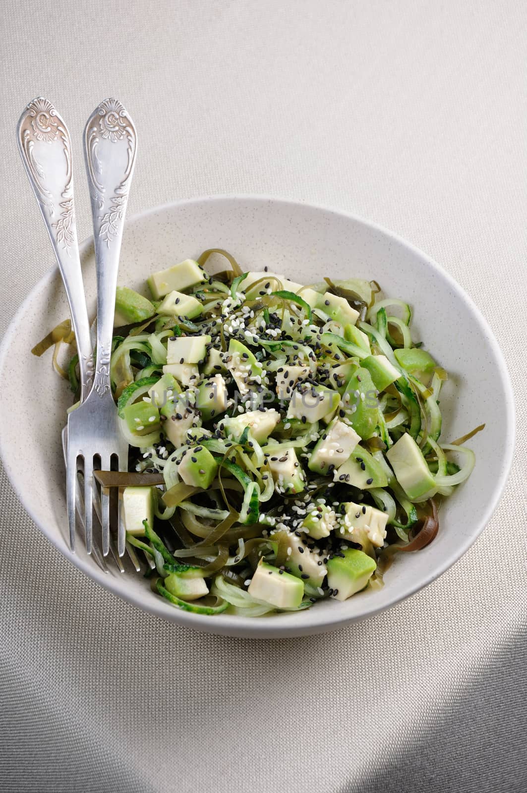 Salad from noodles from cucumbers and laminaria, slices of avocado with sesame