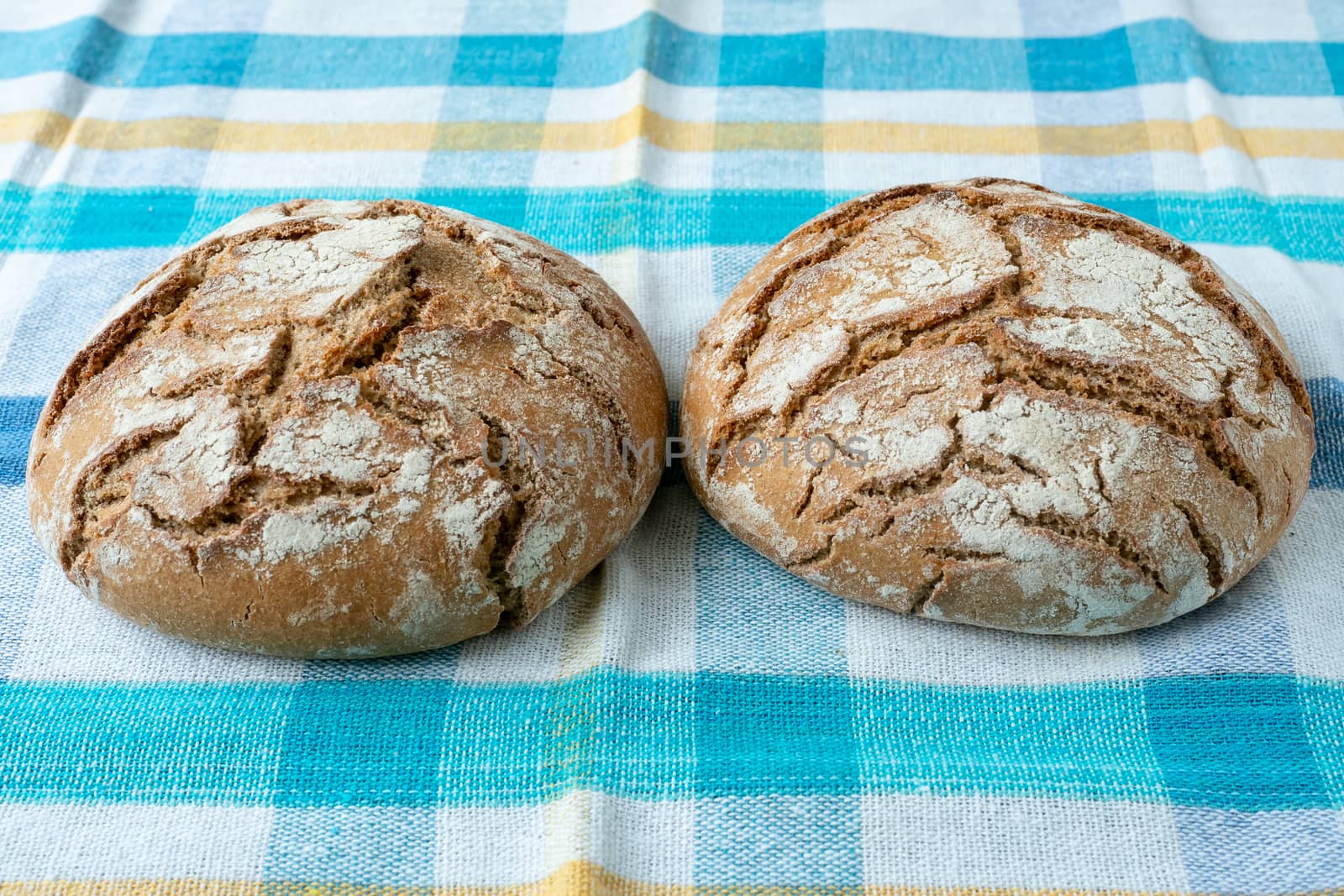 Fresh rustic bread on a checkered towel by xtrekx