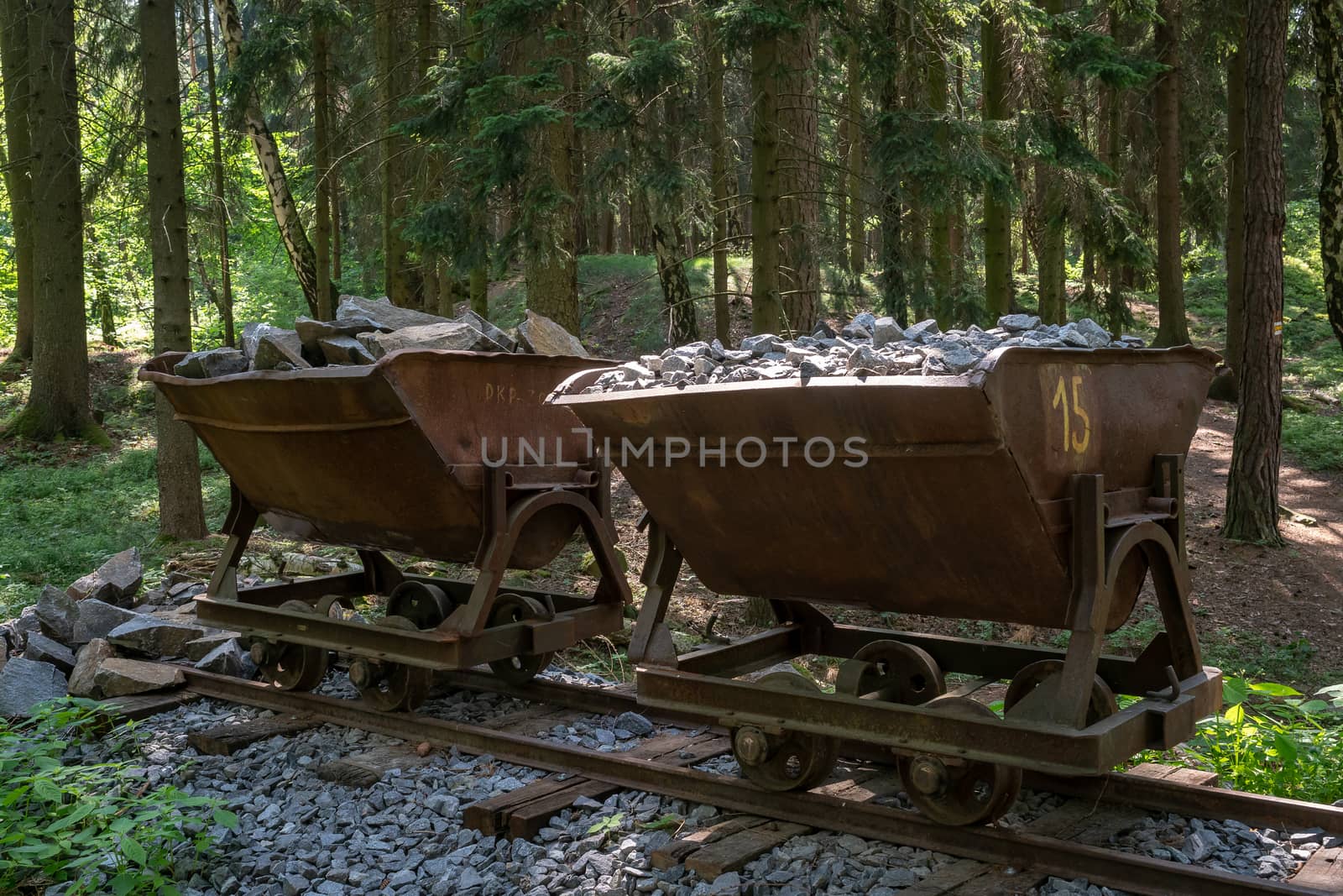 Mining cart with stones. Old and abandoned mining cart in forest by xtrekx