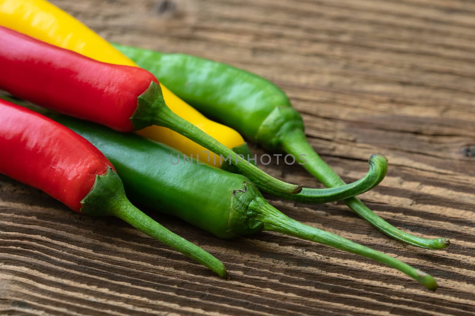 Spicy chilies peppers on wooden background. Colorful peppers on  by xtrekx