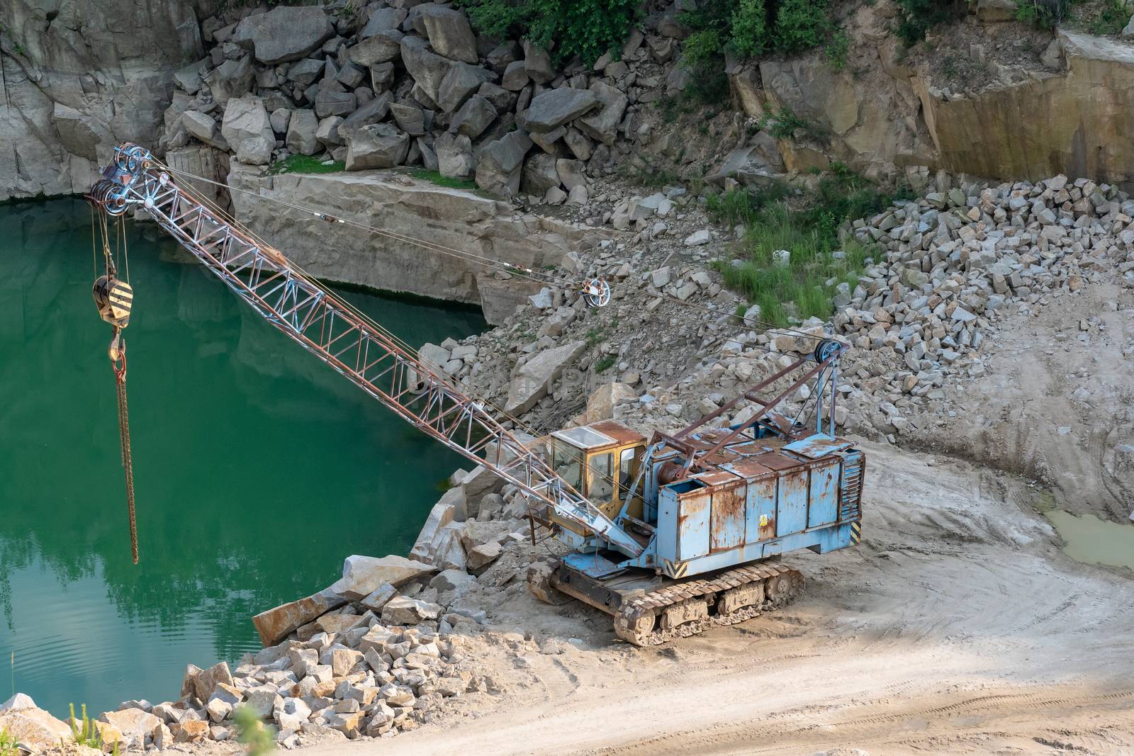 Mining in the granite quarry. Working mining machine - old crane. Mining industry.