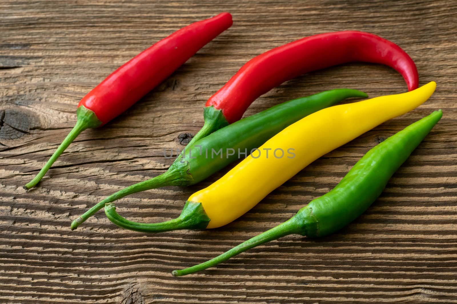 Spicy chilies peppers on wooden background. Colorful peppers on rustic wooden table. Raw healthy food.