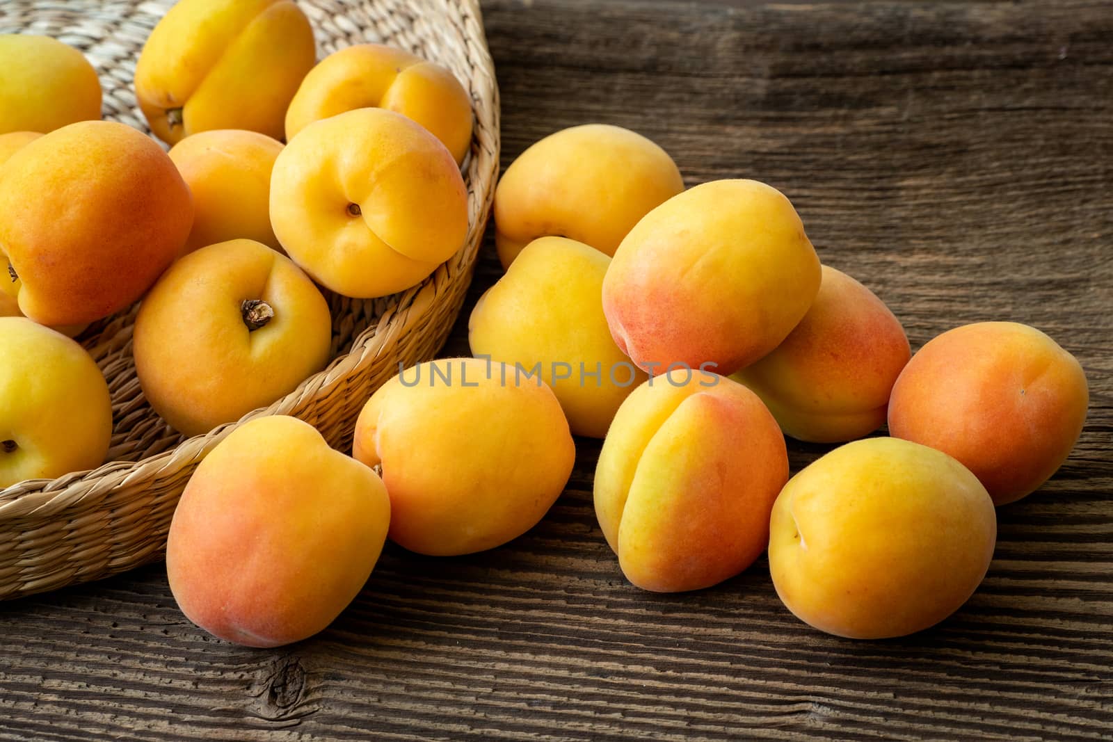 Ripe juicy apricots in a basket on a wooden background by xtrekx