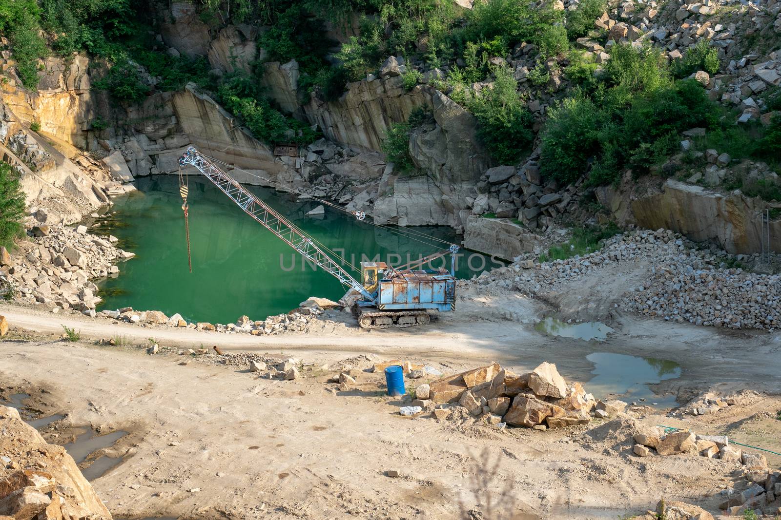 Mining in the granite quarry. Working mining machine - old crane. Mining industry.