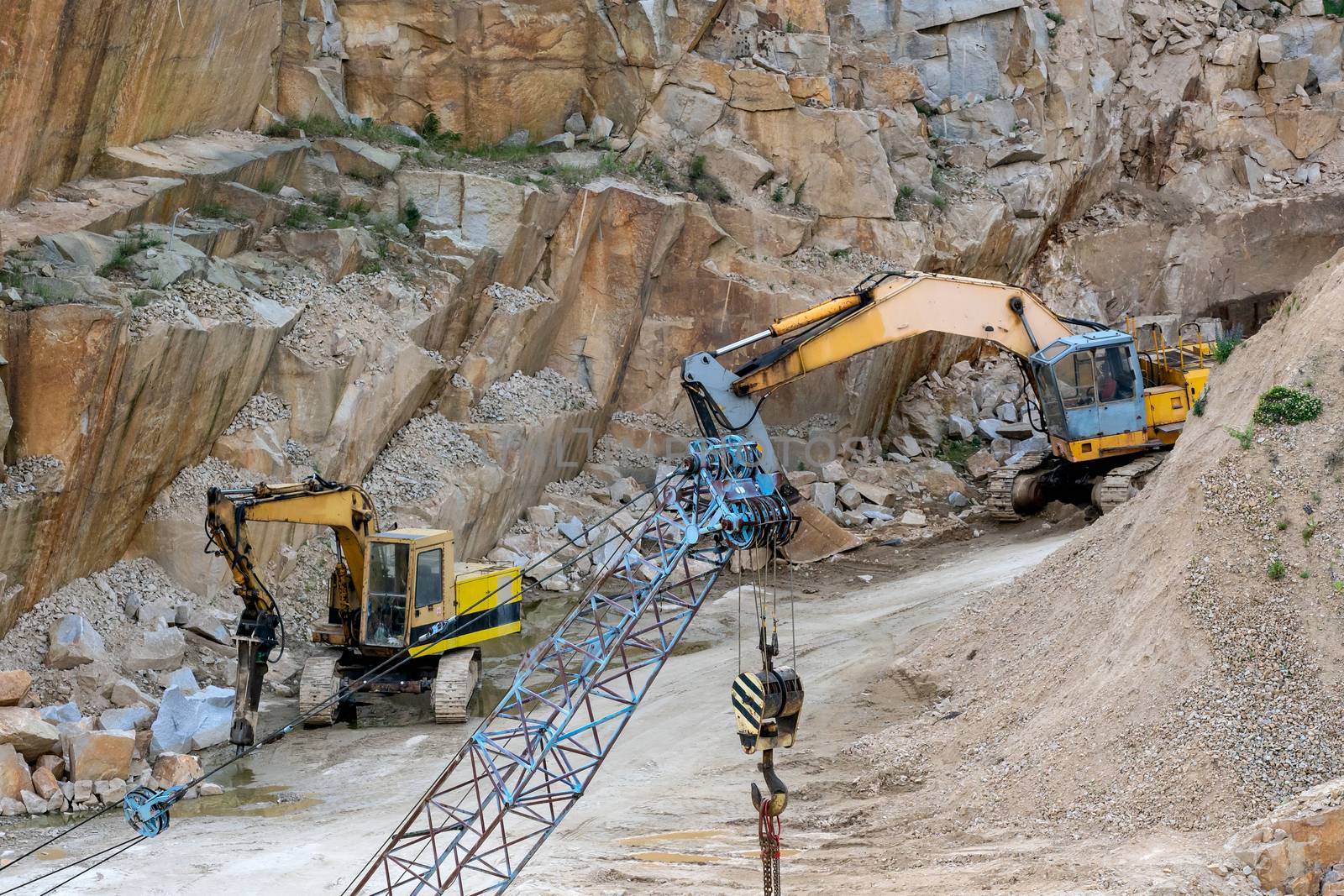 Mining in the granite quarry. Working mining machine - old crane and digger. Mining industry.