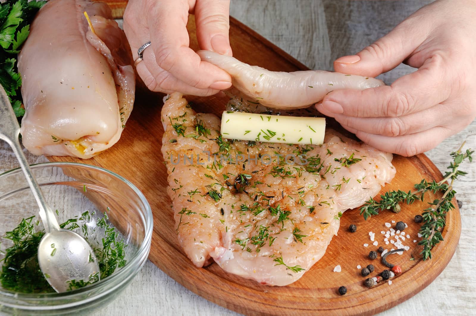 Cooking. A woman's hand, wraps a piece of mozzarella in a chicken breast greased with a dressing with dill. Step-by-step recipe. Stage preparation for cooking dishes. Series.
