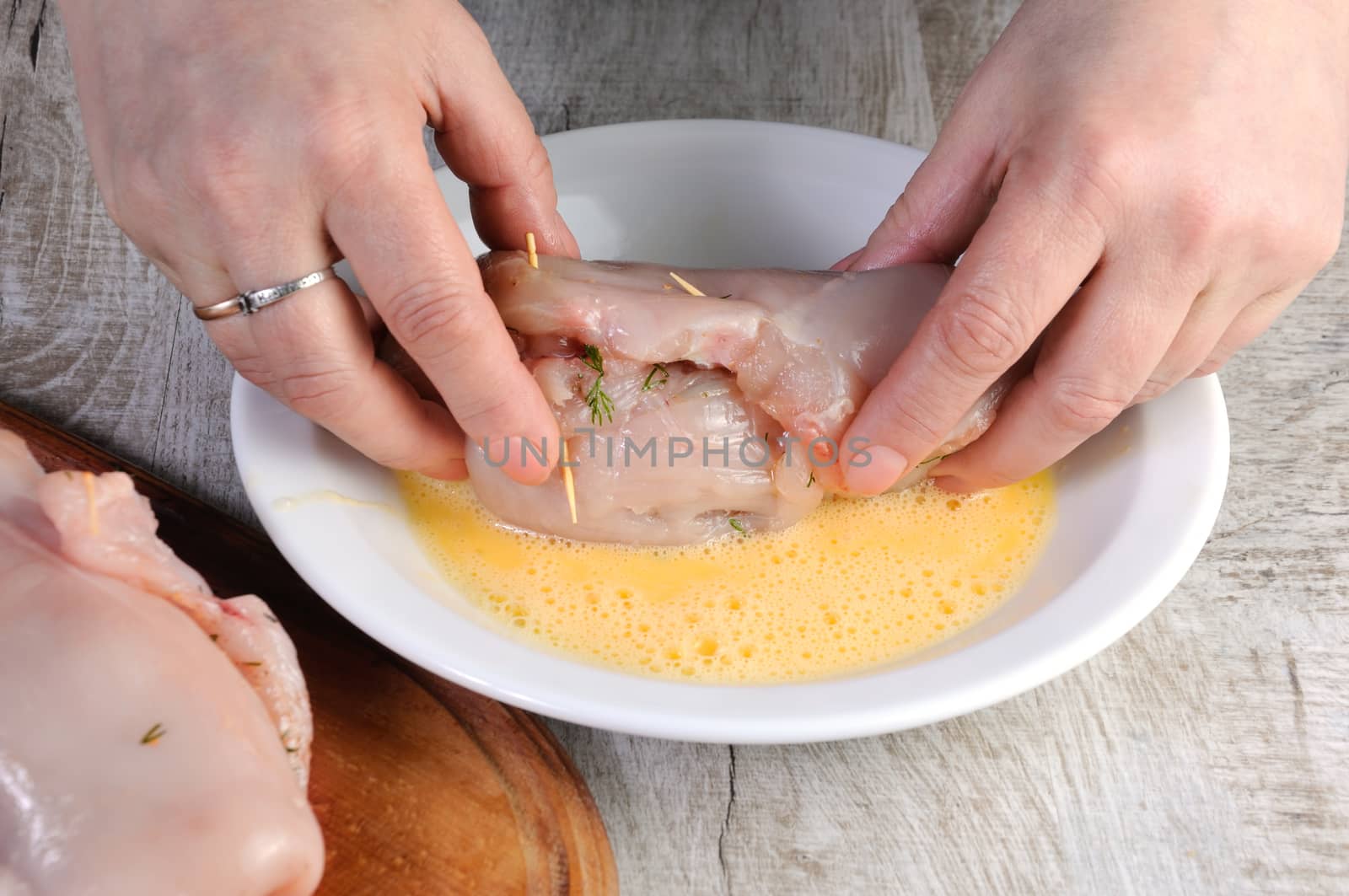 Cooking. A woman's hand dips a stuffed raw chicken breast in an egg. Step-by-step recipe. Stage preparation for cooking dishes. Series.