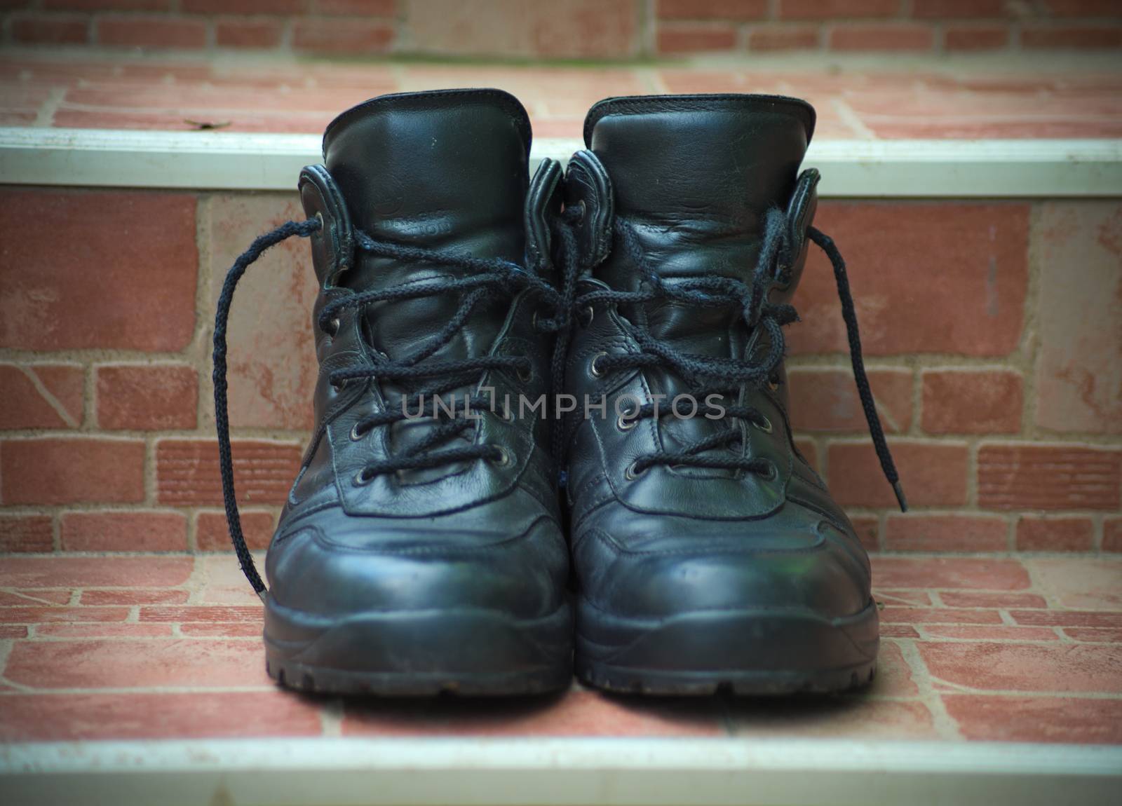 A pair of men black shoes on ceramic tiles stairs, closeup