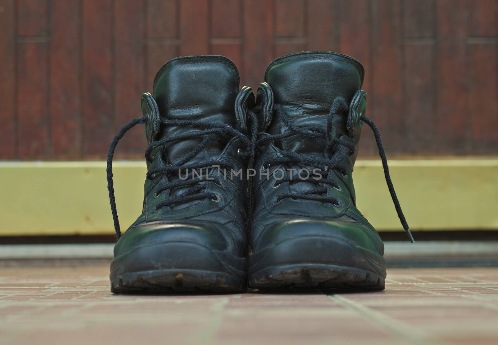 A pair of men black shoes on ceramic stairs in front of door