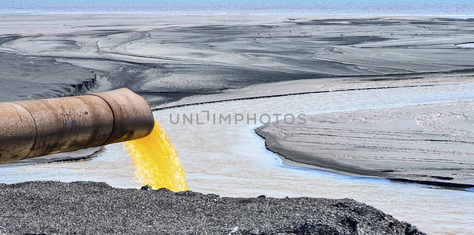 The industrial wastewater is discharged from the pipe into the water.