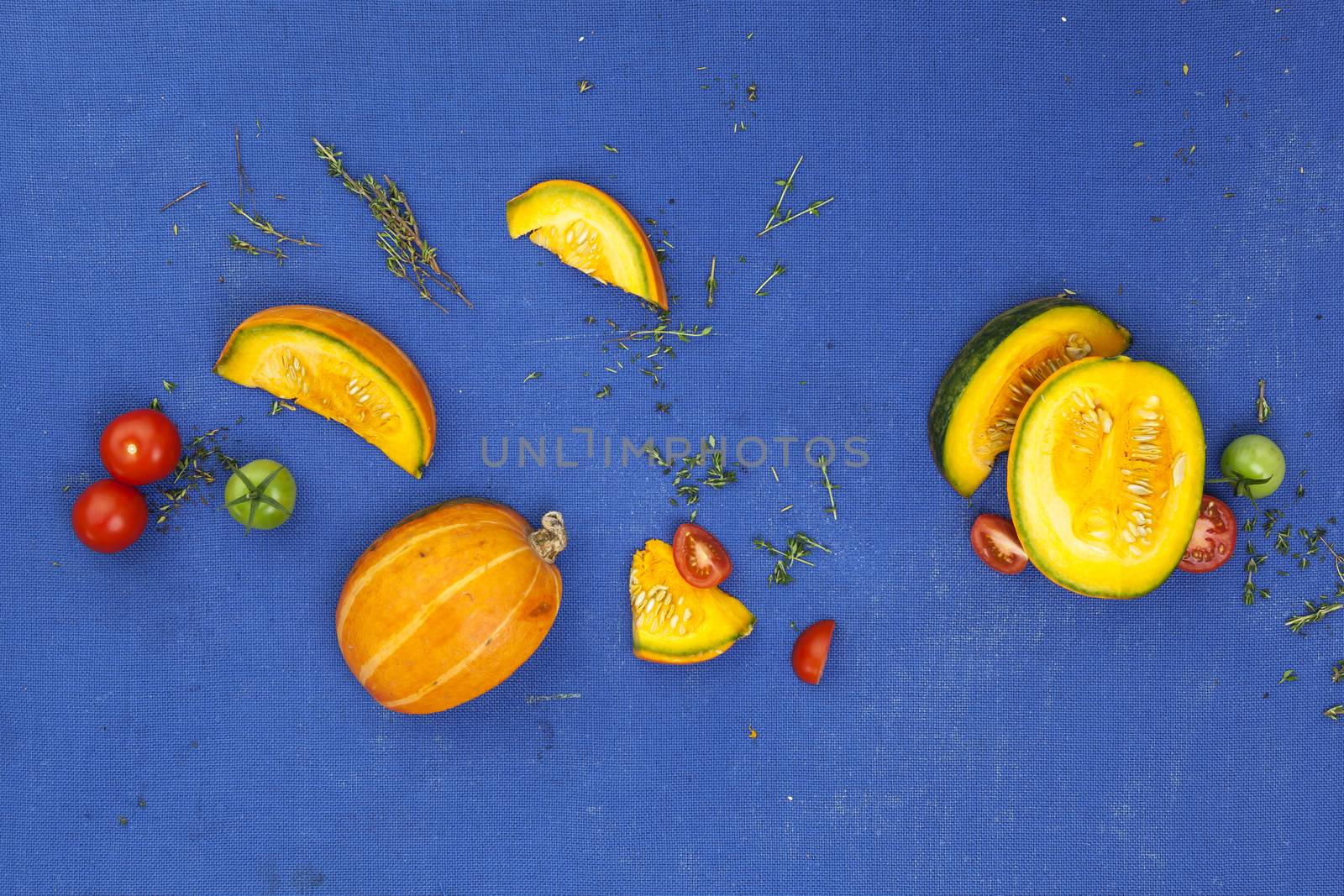 Food concept background. Pumpkin, tomatoes and thyme on blue table. Top view by xamtiw
