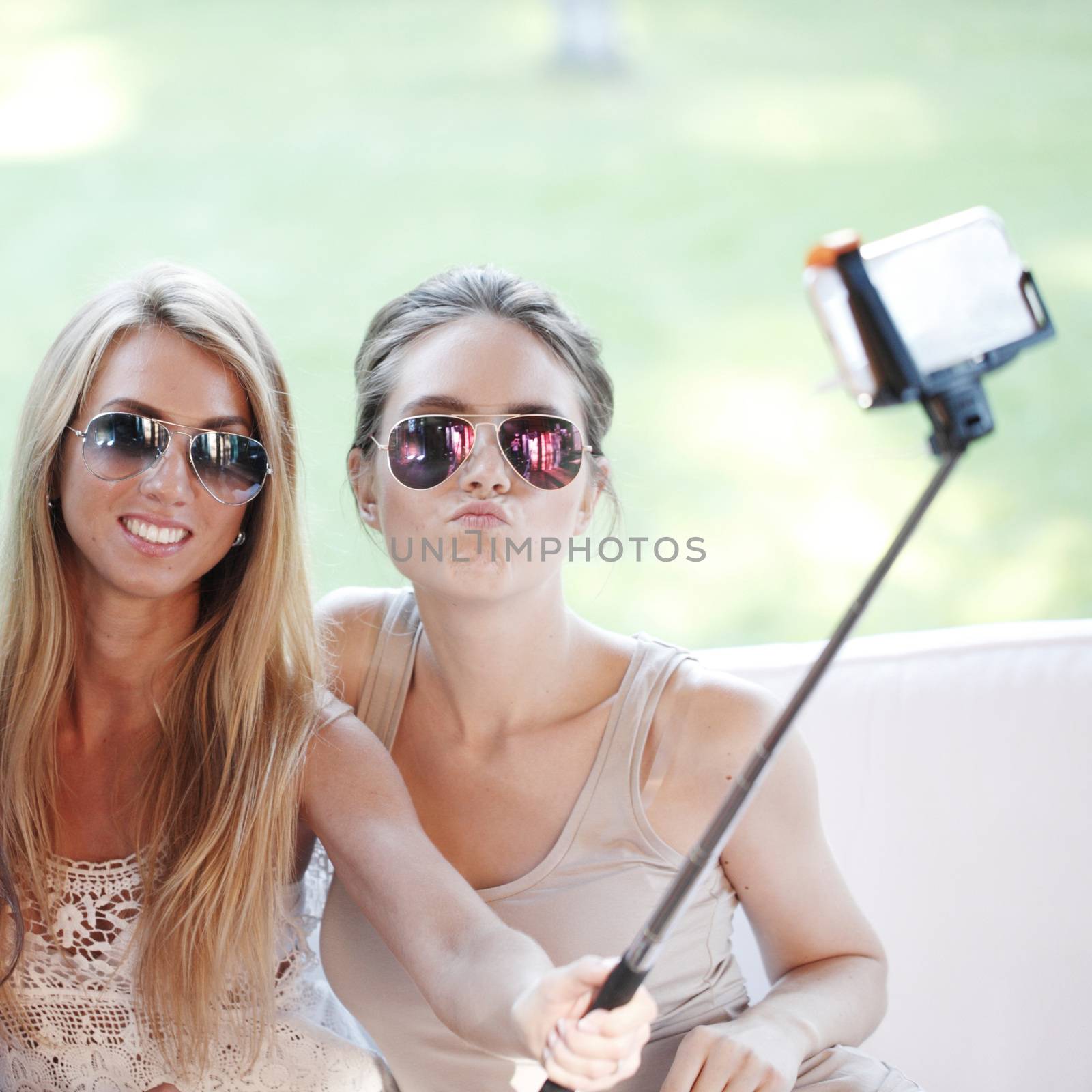 Young beautiful female friends taking selfie outdoors