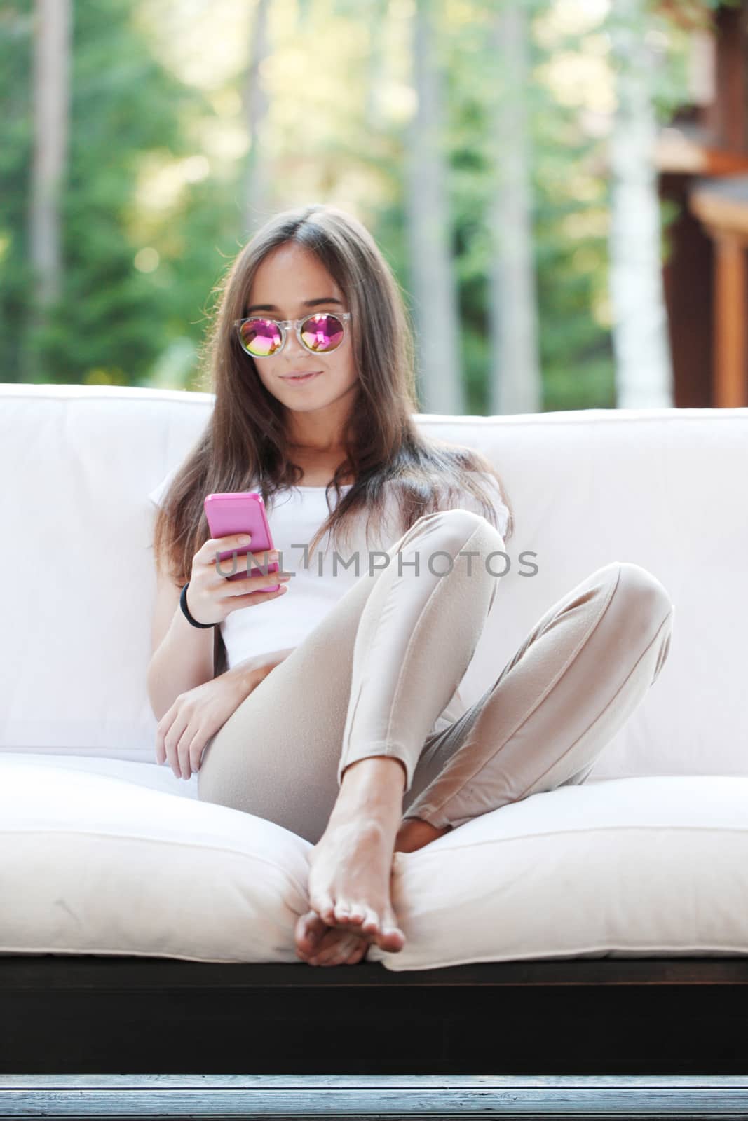 Beautiful young girl with smartphone sitting outdoors