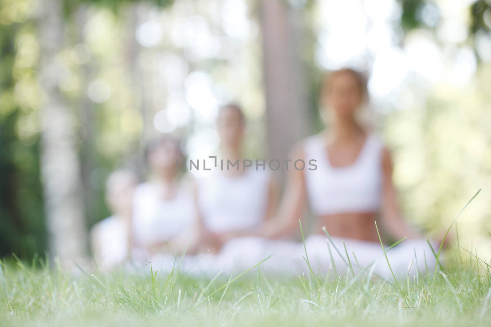 Abstract defocused background of women sitting in lotus position during yoga training at park