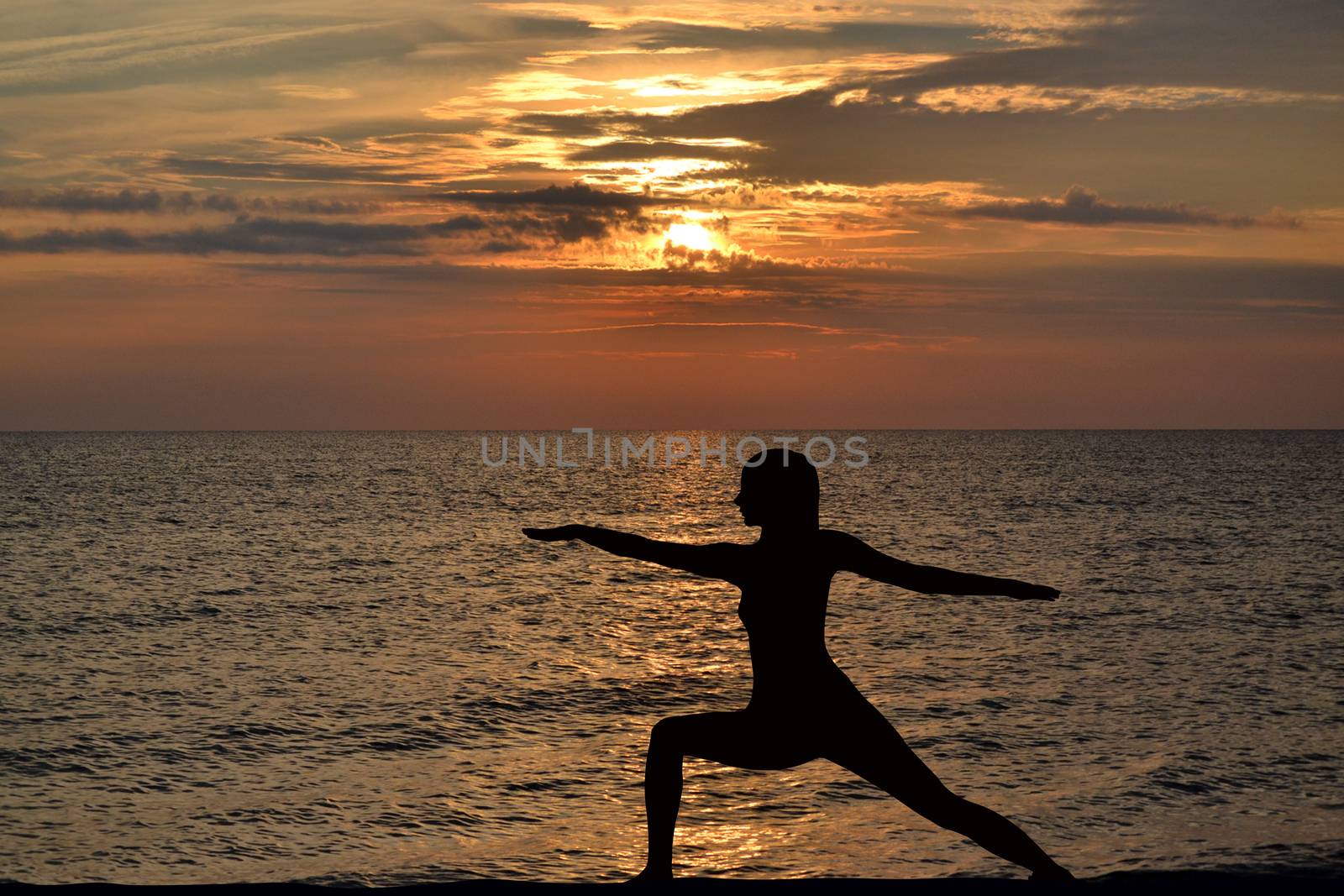 Woman practicing yoga, standing in pose at sunrise