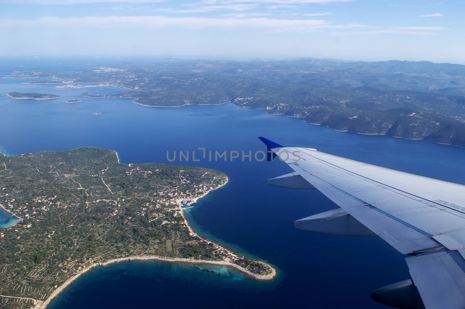 Airplane wing and Croatia land in summertime on a sunny day.