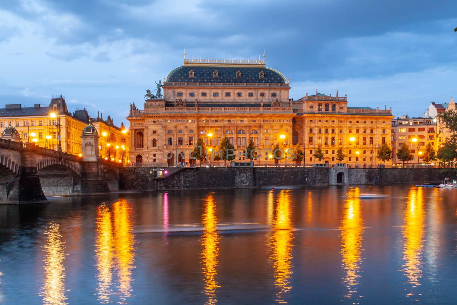 Prague National Theatre by night. Illuminated embankment and Vltava River. Prague, Czech Republic.